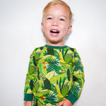 Child wearing a green jungle-themed pajama set on a white background