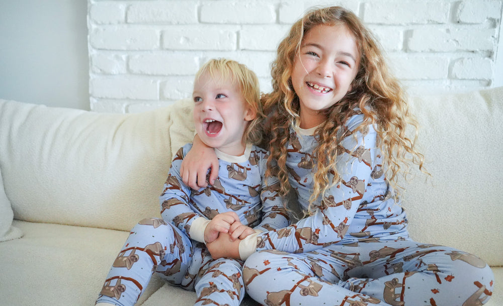 two children hugging and smiling in sloth print pajamas